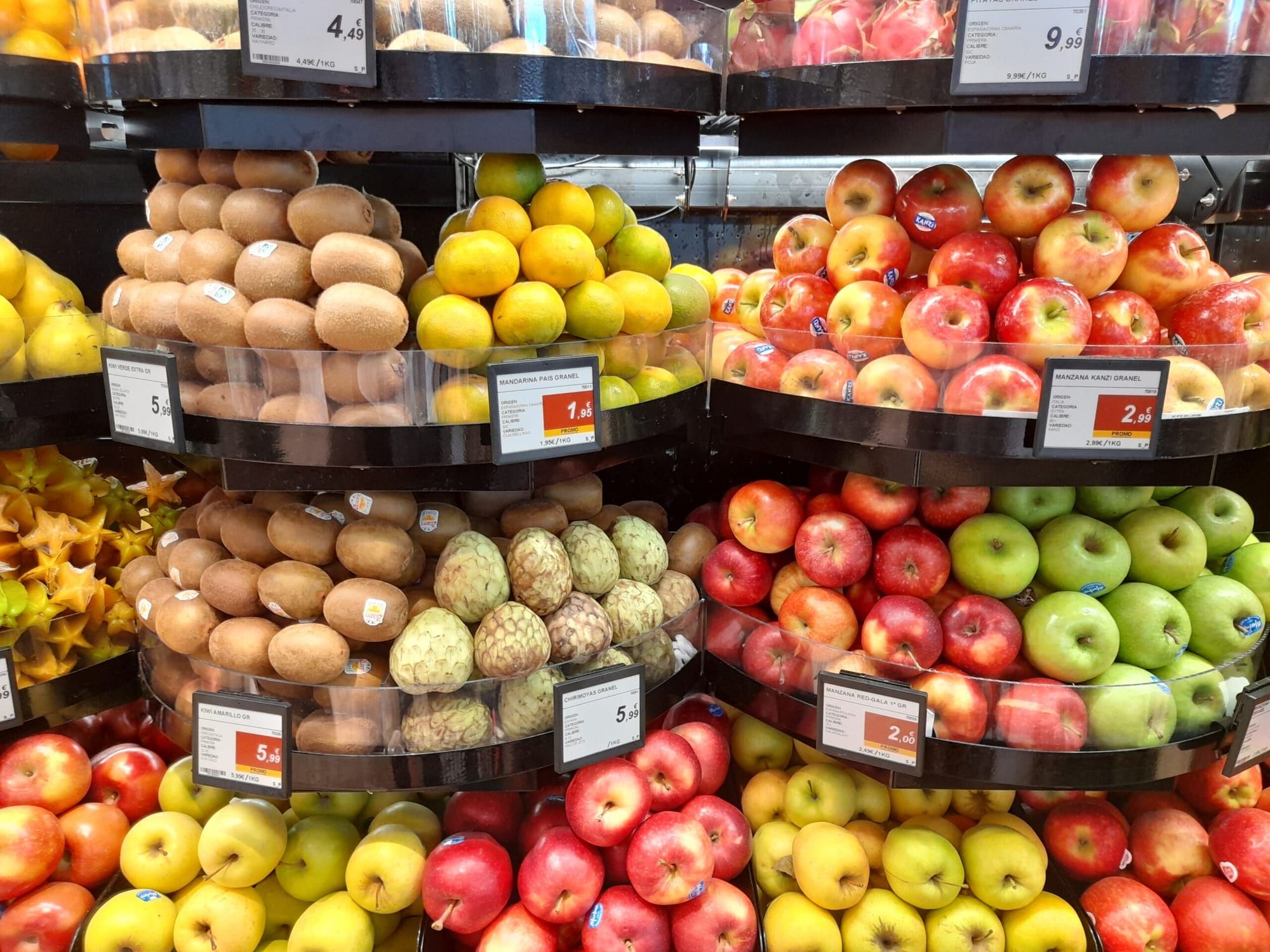 Frutería con expositores de manzanas y una etiqueta electrónica de precio por kilo en cada uno