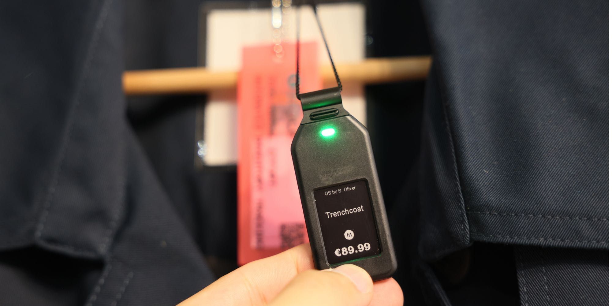 Etiqueta electrónica colgante en una gabardina, con el precio y el LED de localización encendido